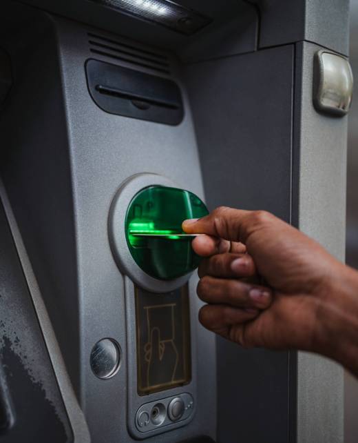 Close up shot of a man inserting a credit card in an ATM outdoors to check the bank account.